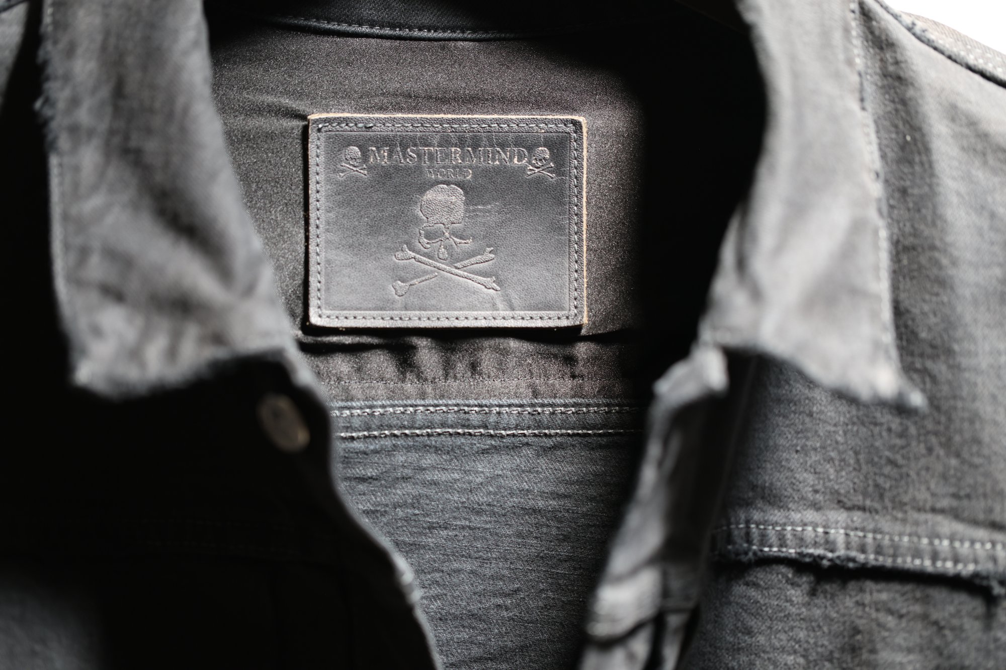 Embossed leather brand patch at the inside collar, framed by the open placket.