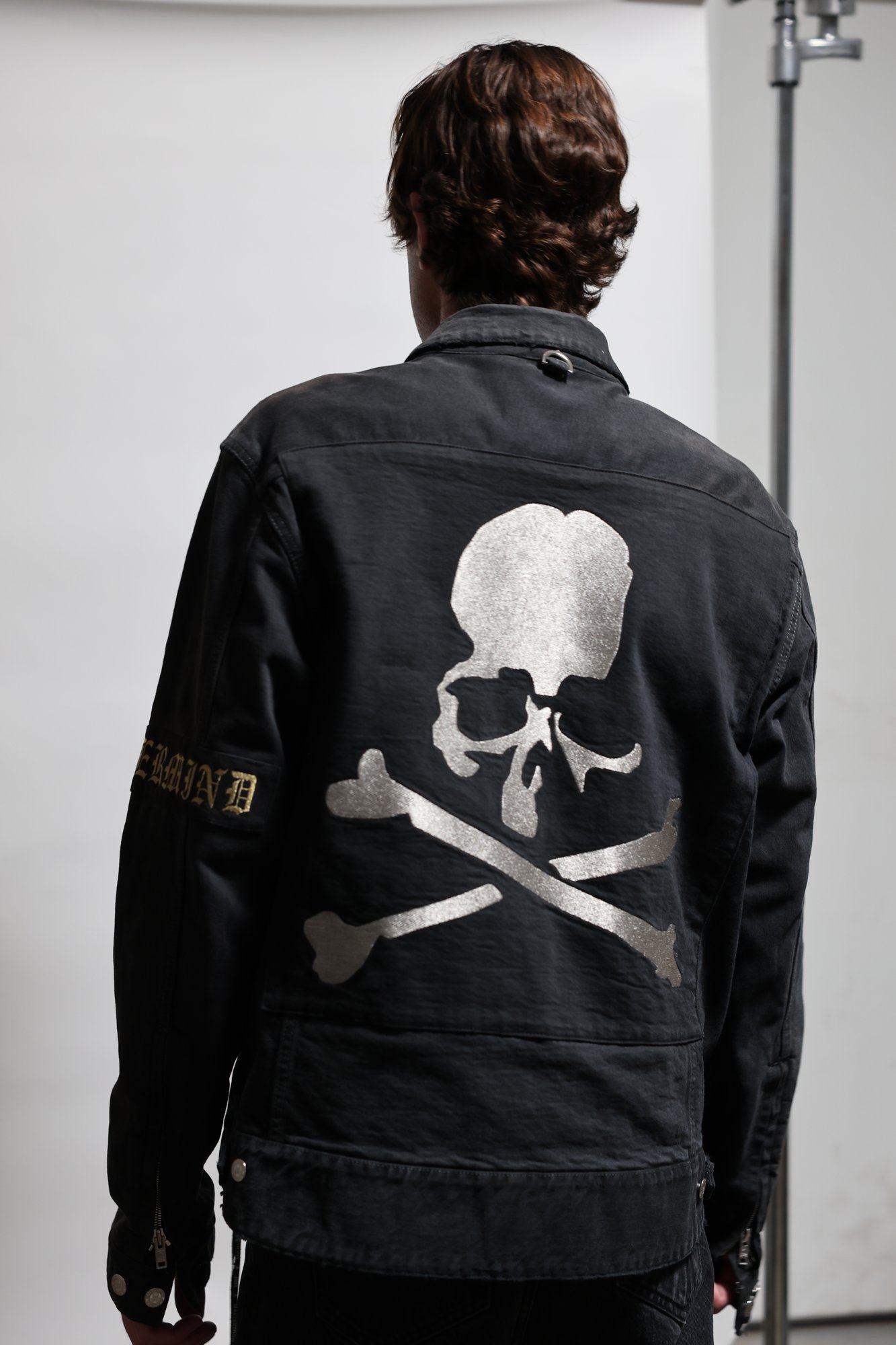 The jacket worn, back to camera, glitter skull and crossbones across the shoulders.